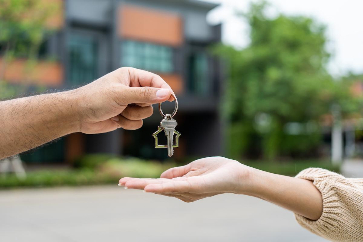 Investing in Cedar City Woman buying or rent new home she holding key front of new house.