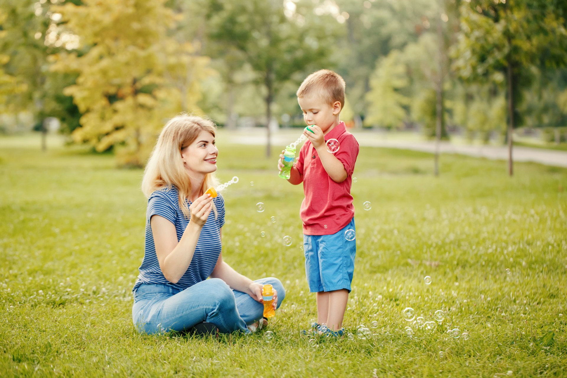simplify-life-getty-images-7L6GTxJNVhE-unsplash (1) Woman and child playing with bubbles in a grass field